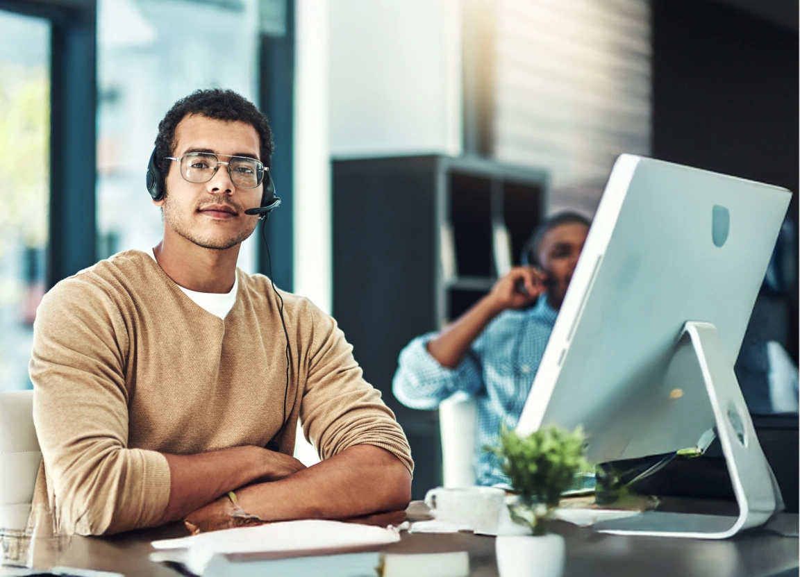 Portrait of a businessman at a call center desk with a headset offering service and support